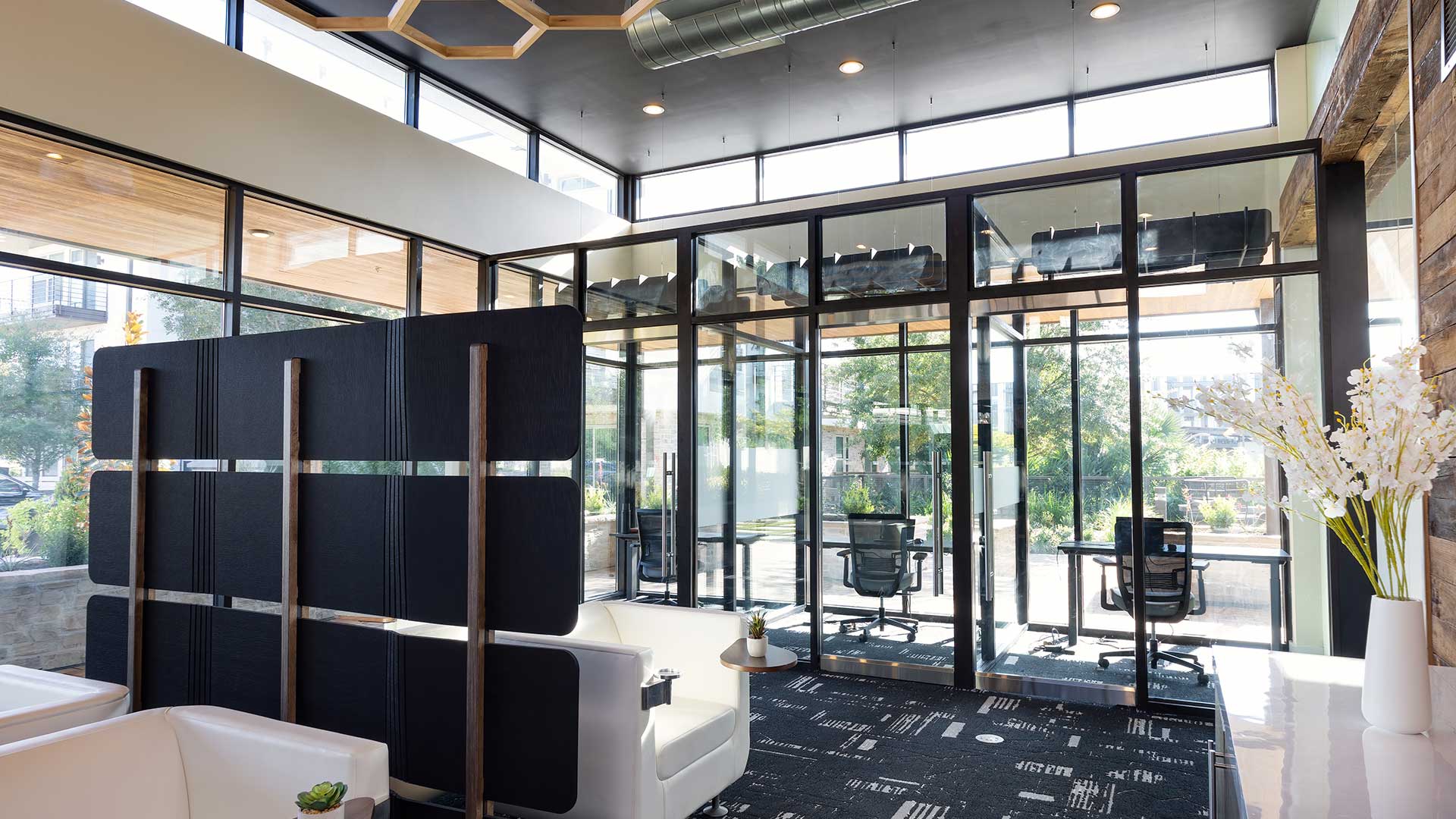 A modern co-working space with a glass wall and black chairs.
